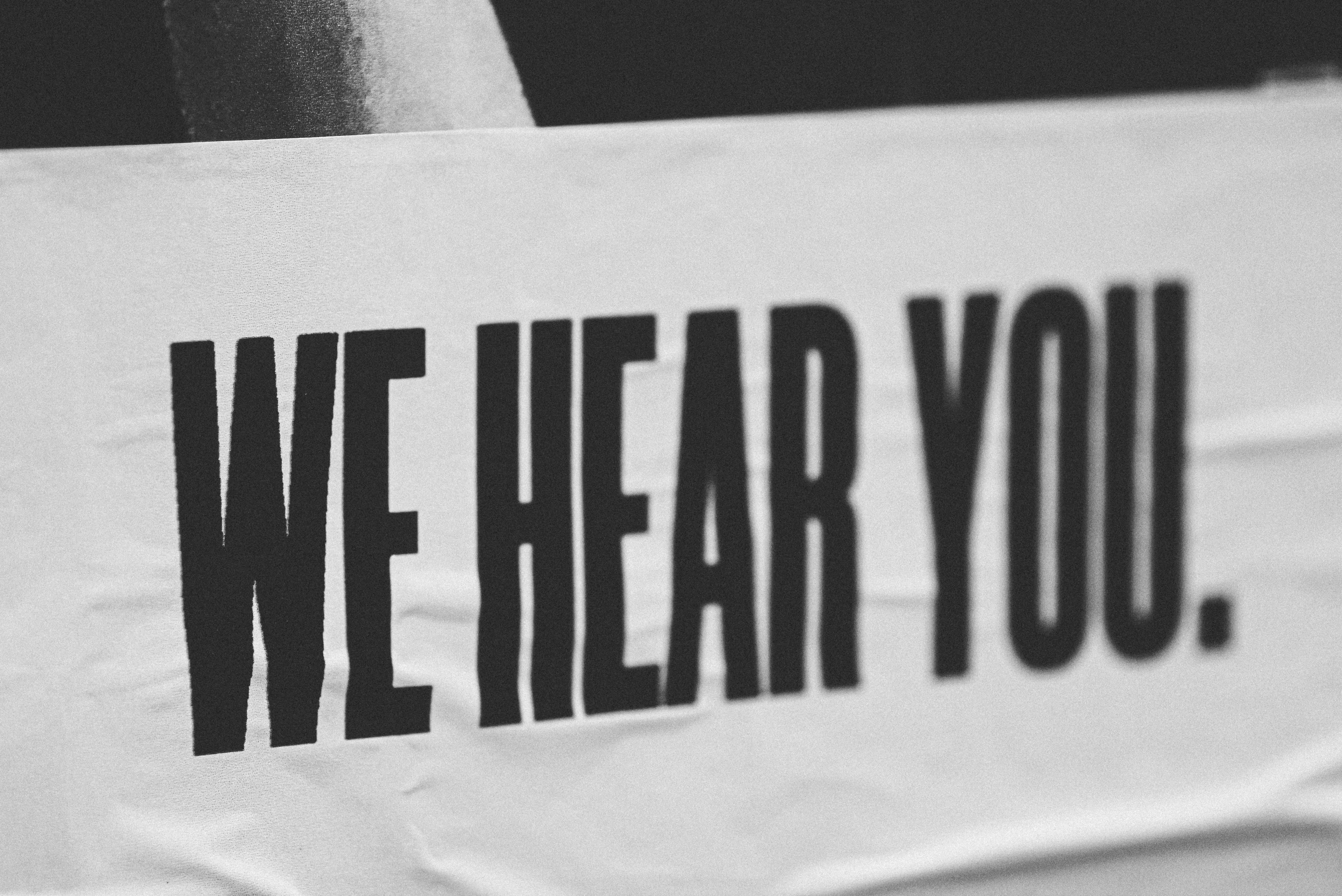 A paper sign with the words, "We hear you."