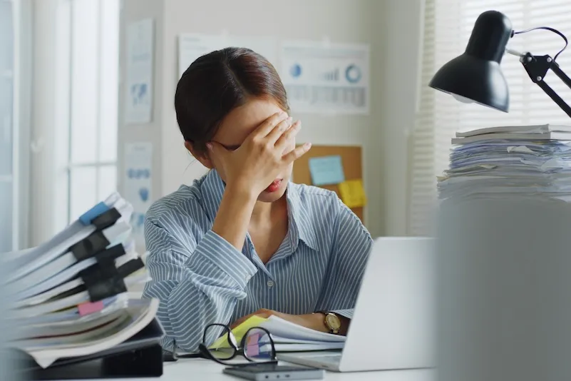 An overwhelmed woman surrounded by paperwork