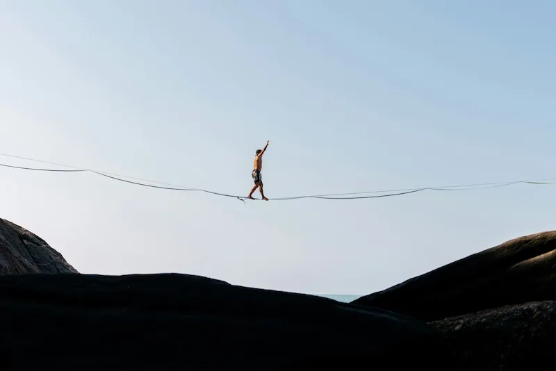 A tightrope walker crossing over boulders.